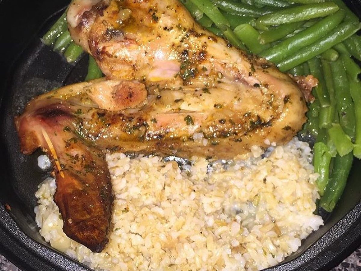 Roasted chicken over rice with green beans in a black tray